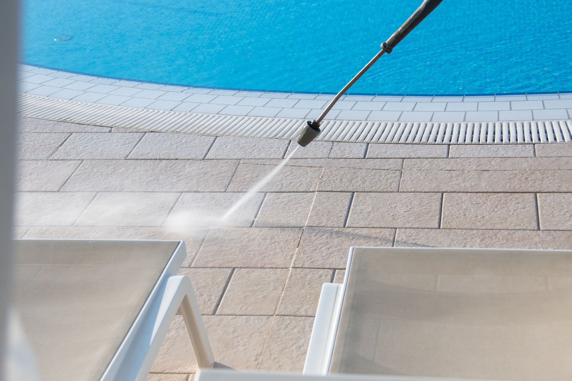 High-Pressure Cleaning of Poolside Tiles with Water Jet on Sunny Day, Outdoor Pool Maintenance and Hygiene